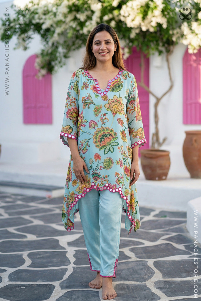 Woman wearing a colorful floral dress with a white background and pink shutters.