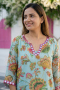 Woman wearing a floral embroidered dress with colorful patterns.