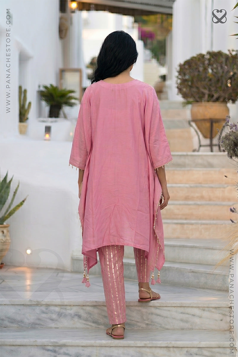 Woman in a pink kaftan top and zari strip pants standing on steps