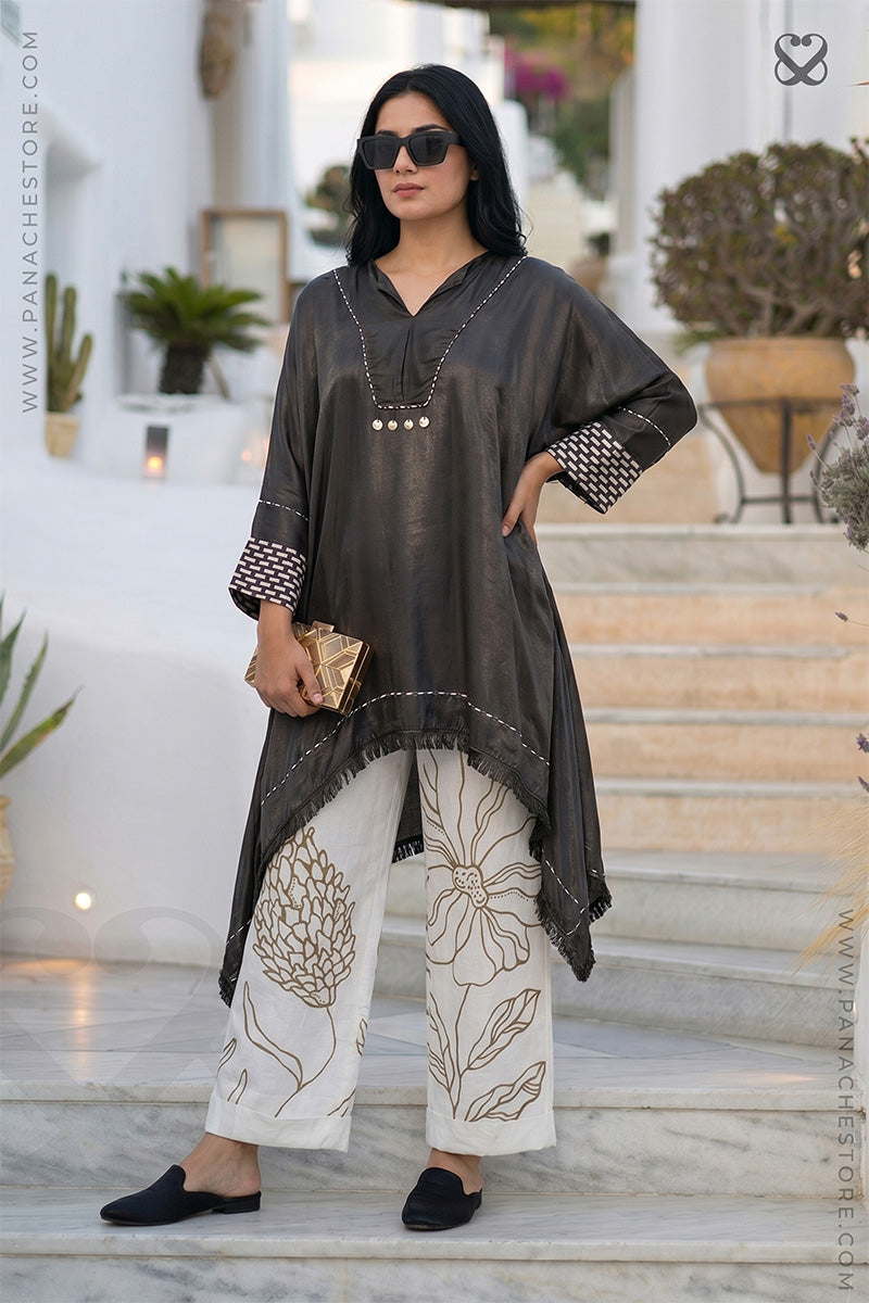 Woman wearing a shiny black long-sleeve kurti top and white hand painted floral pattern on pant standing on steps