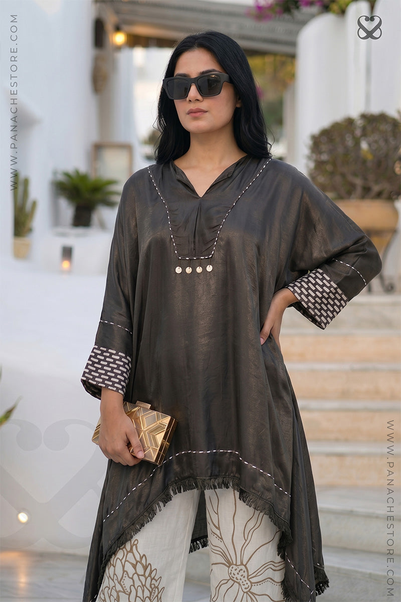 Woman wearing a shiny black kurti top and white hand painted pant in an outdoor setting.
