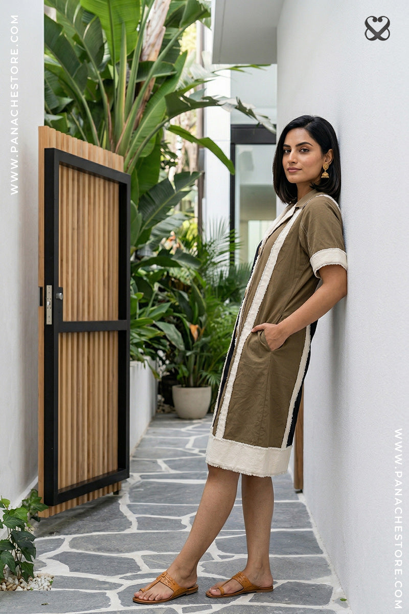 Woman in a green dress standing in a modern outdoor setting with plants and a wooden door.