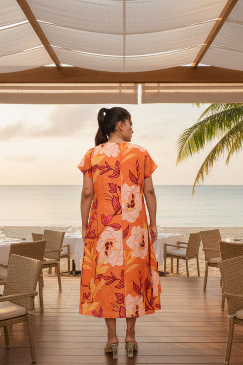 Woman in an orange floral dress standing in a beachside restaurant.