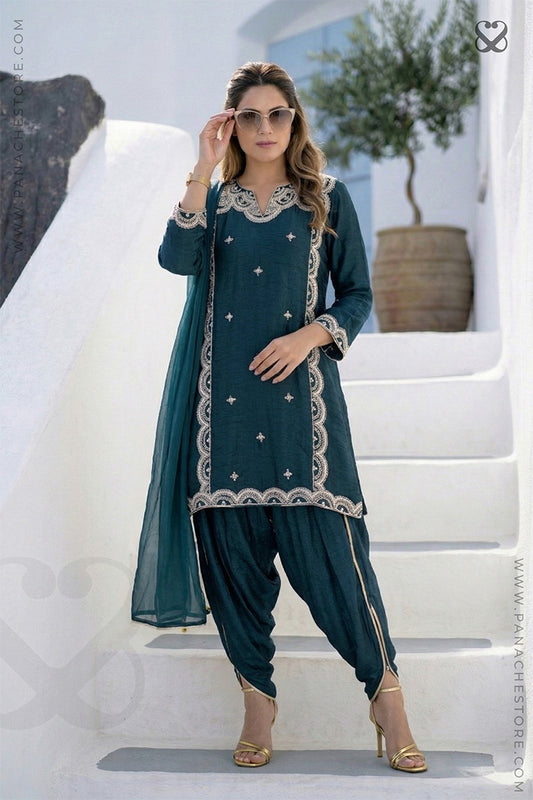 Woman in deep teal green embroidered kurti and pajama pant standing on steps