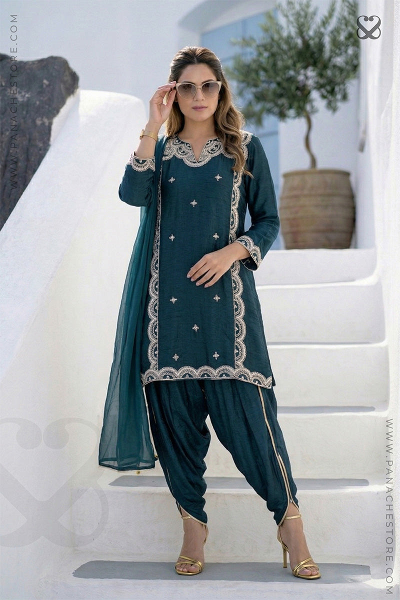 Woman in deep teal green embroidered kurti and pajama pant standing on steps