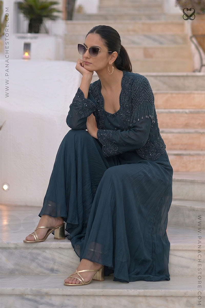Woman wearing a designer deep peacock teal heavy embellished top with matching skirt sitting on steps