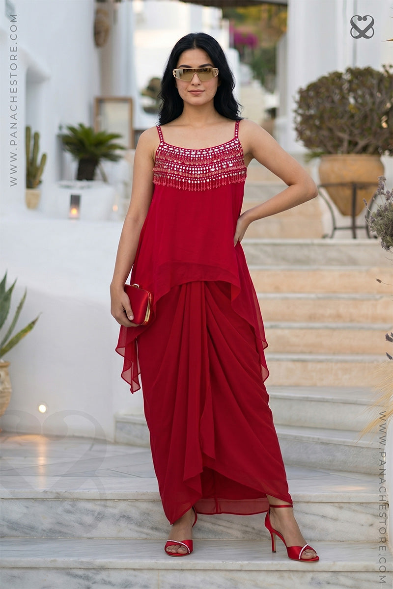 Woman in a red party wear dress standing on marble steps apearing a georgeous paty ready look