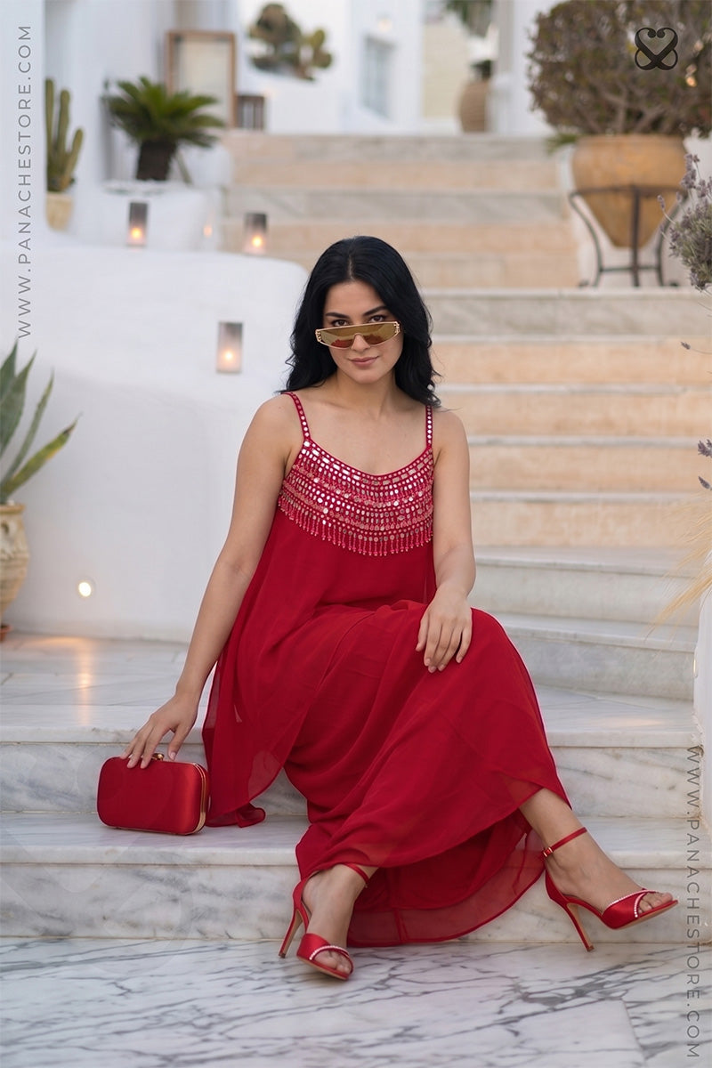 Woman in a red dress sitting on marble steps apearing a perffect georgeous paty ready look