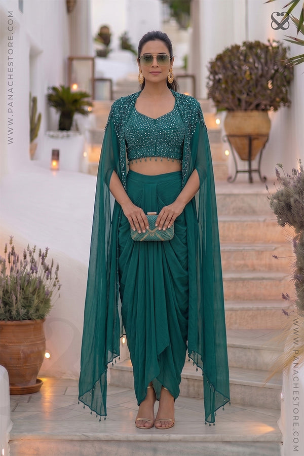 Woman wearing a designer teal sapphire green embellished blouse top & shrug with matching dhoti style skirt sitting on steps