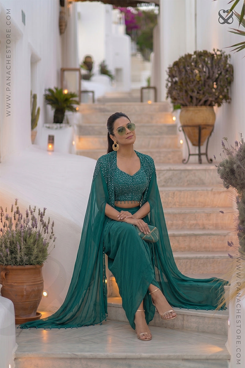Woman wearing a designer teal sapphire green embellished shrug & blouse top with matching skirt sitting on steps