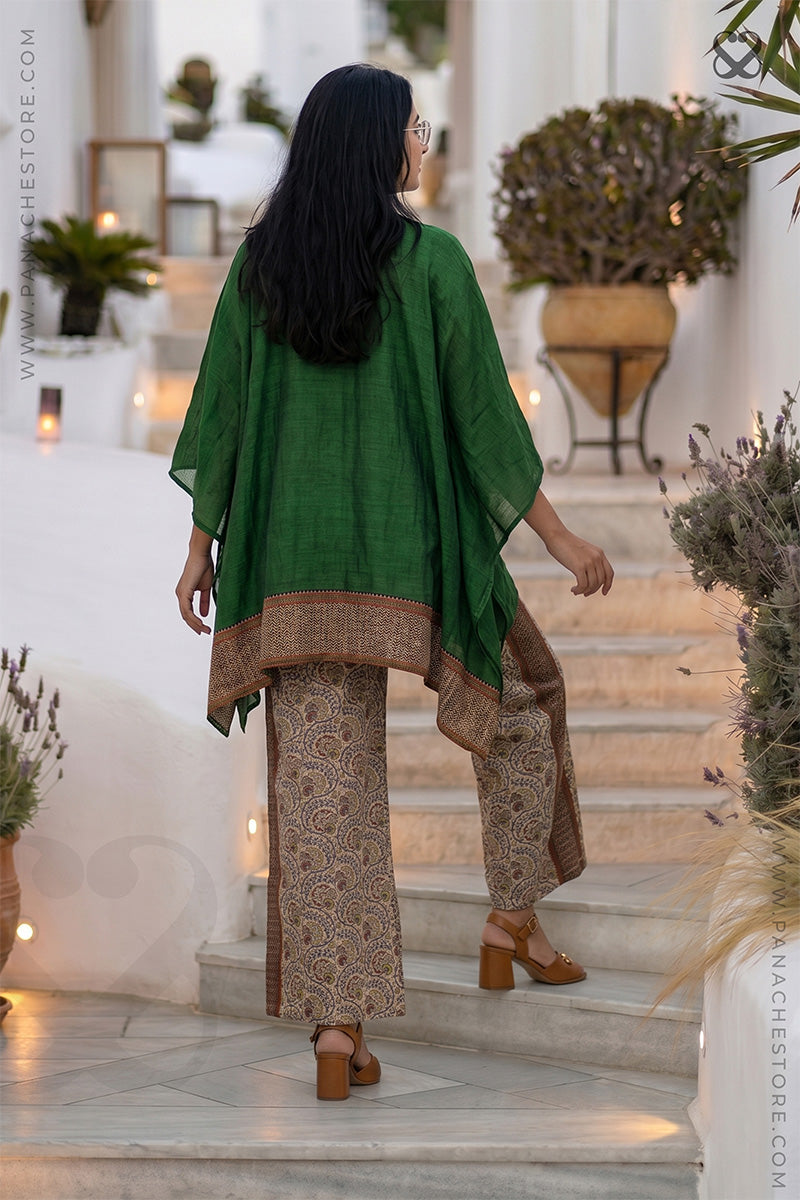 Woman in a green and beige Kaftan and printed beige pant outfit moving up on steps