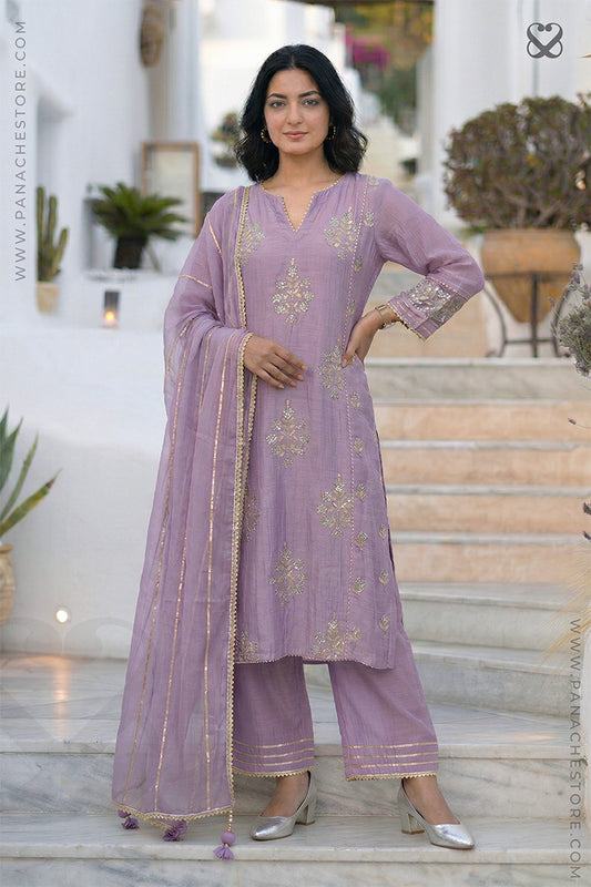 women in a lavender kurti salwar suit with embellishments and matching pant standing on steps
