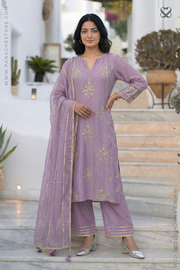 women in a lavender kurti salwar suit with embellishments and matching pant standing on steps