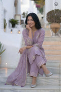 women in a lavender kurti salwar suit with embellishments and matching pant sitting on steps