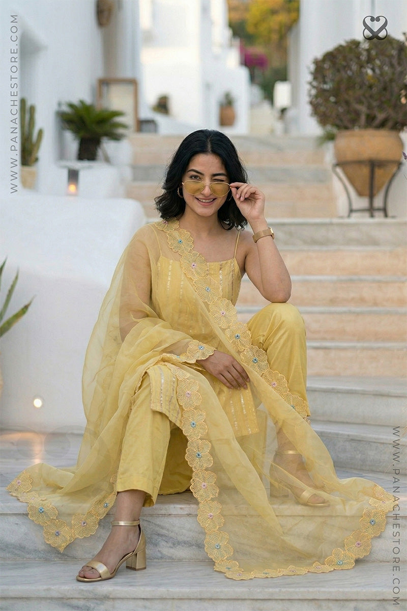 women in a yellow zari woven sleeveless kurti top with embroidered cutwork dupatta and pant sitting on steps