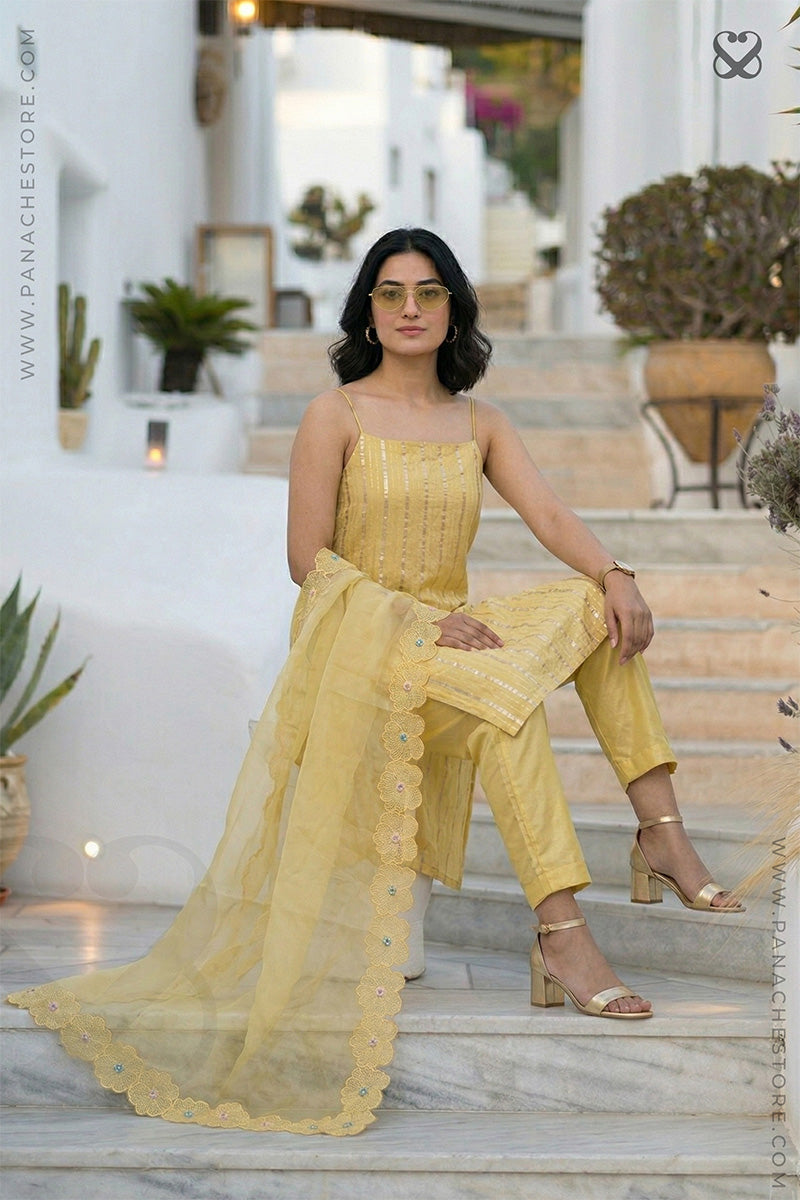 women in a yellow zari woven sleeveless kurti top with embroidered cutwork dupatta and pant sitting on steps