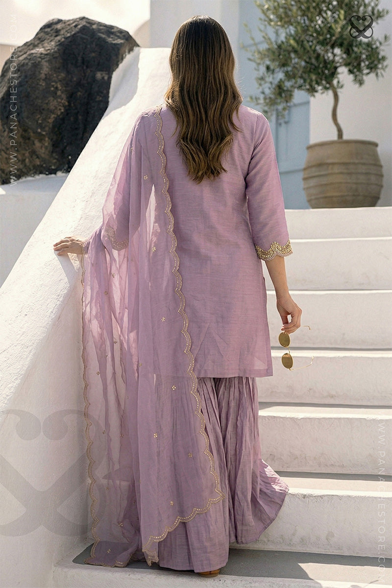 Woman wearing a lavender salwar suit set and dupatta with gold embellishments moving up on steps