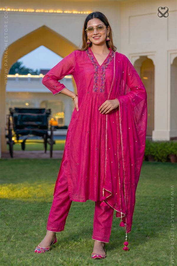 Woman in a deep pink salwar suit set and organza dupatta standing on steps