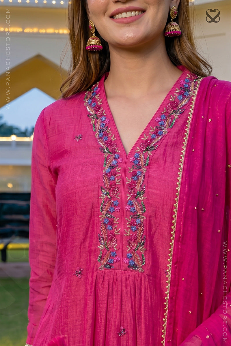 Woman wearing a pink embroidered kurti outfit with a blurred background