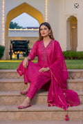 Woman in a deep pink salwar suit set and organza dupatta sitting on steps