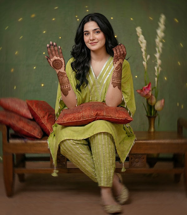An Indian female in green outfit making a Mehendi Henna ceremony look outfit shot.