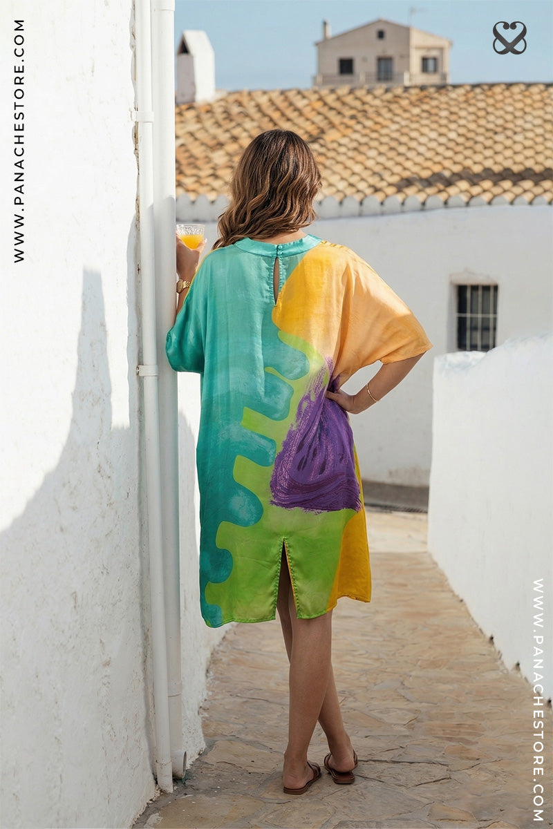 Woman in a colorful dress standing on a sunlit rooftop with white walls and orange tiles.