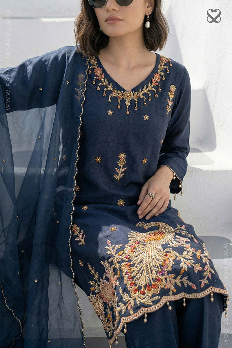 Woman wearing a deep peacock blue embroidered salwar suit set with a sheer dupatta.