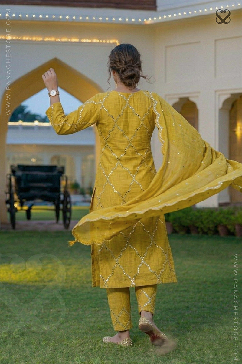 Woman in a yellow designer suit set with mirror work and matching dupatta dancing in a garden