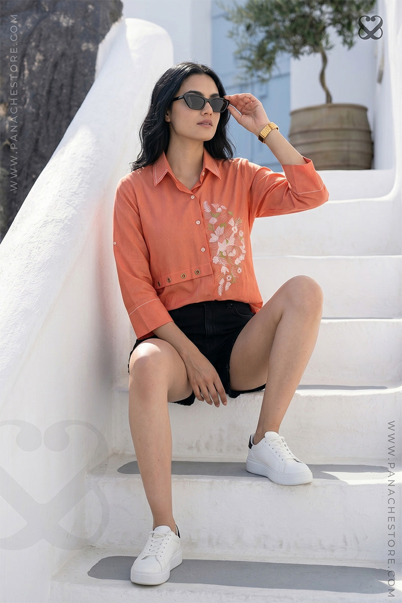 Woman in orange shirt with floral embroidery sitting on steps
