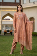 Woman in a tissue silk peach salwar suit with dupatta standing in a garden