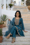 Woman in a peacock blue designer Suit outfit sitting on steps with plants in the background