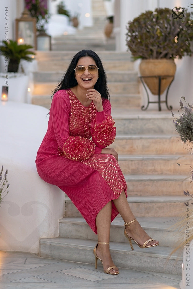 Woman in a pink designer party wear dress with ruffled floral sleeves sitting on steps