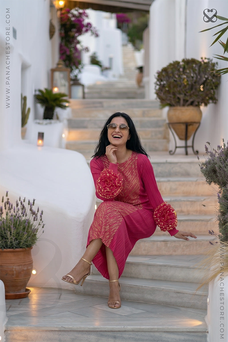 Woman in a pink designer party wear dress with ruffled floral sleeves sitting on steps