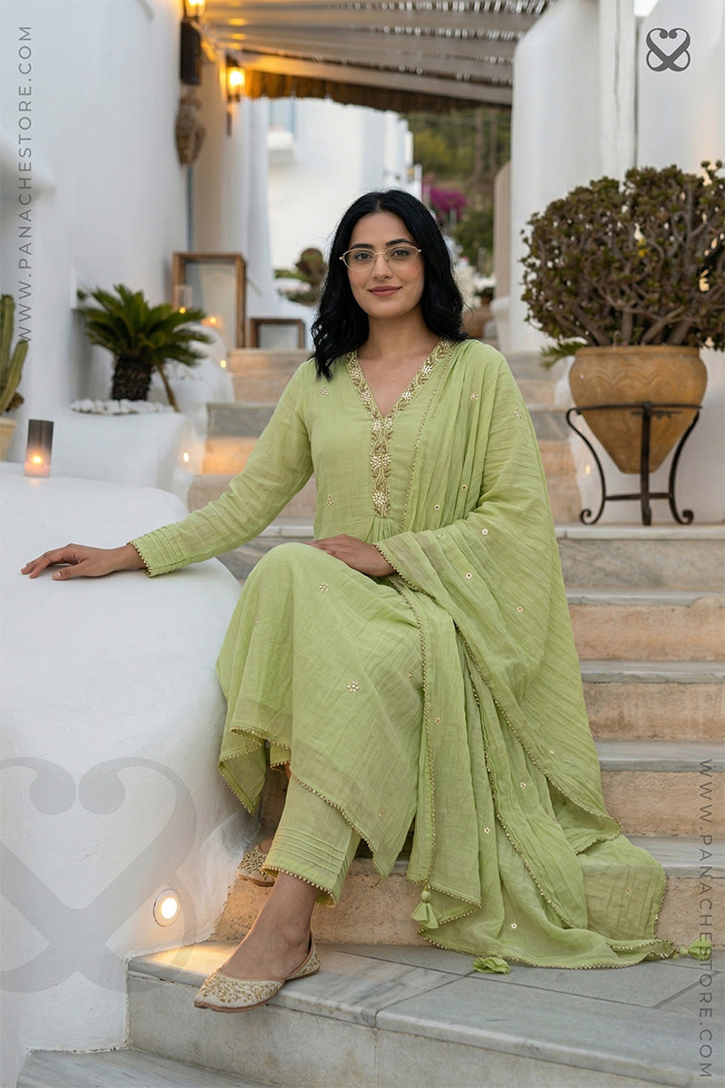 Woman in a light green traditional cotton 3 piece suit set outfit sitting on steps outdoors.