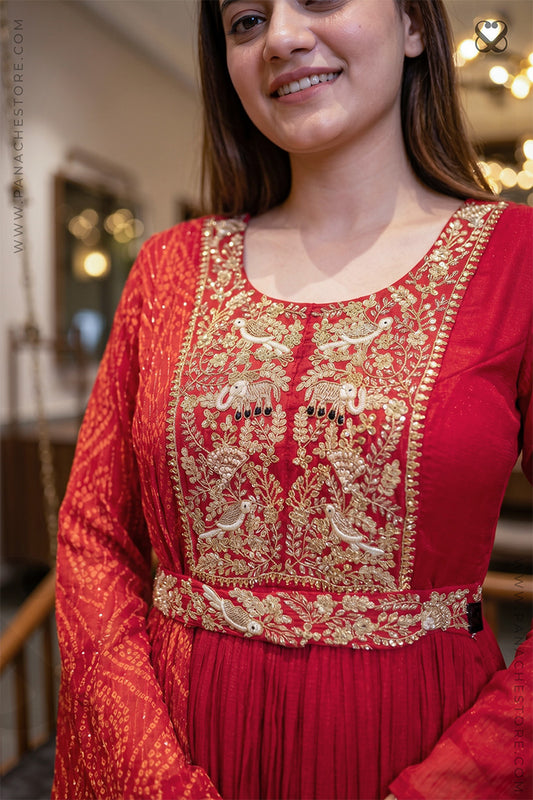 Woman wearing a red traditional outfit with gold embroidery in an indoor setting.