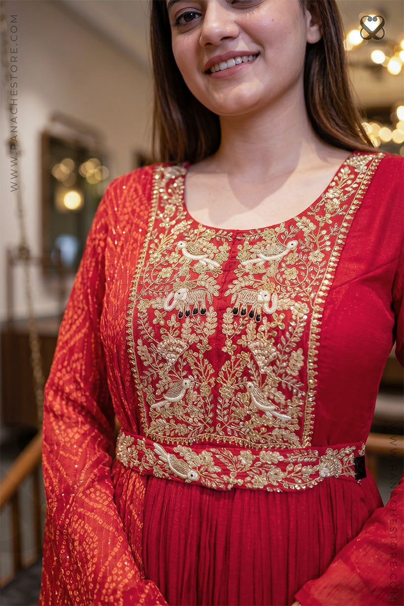Woman wearing a red traditional outfit with gold embroidery in an indoor setting.