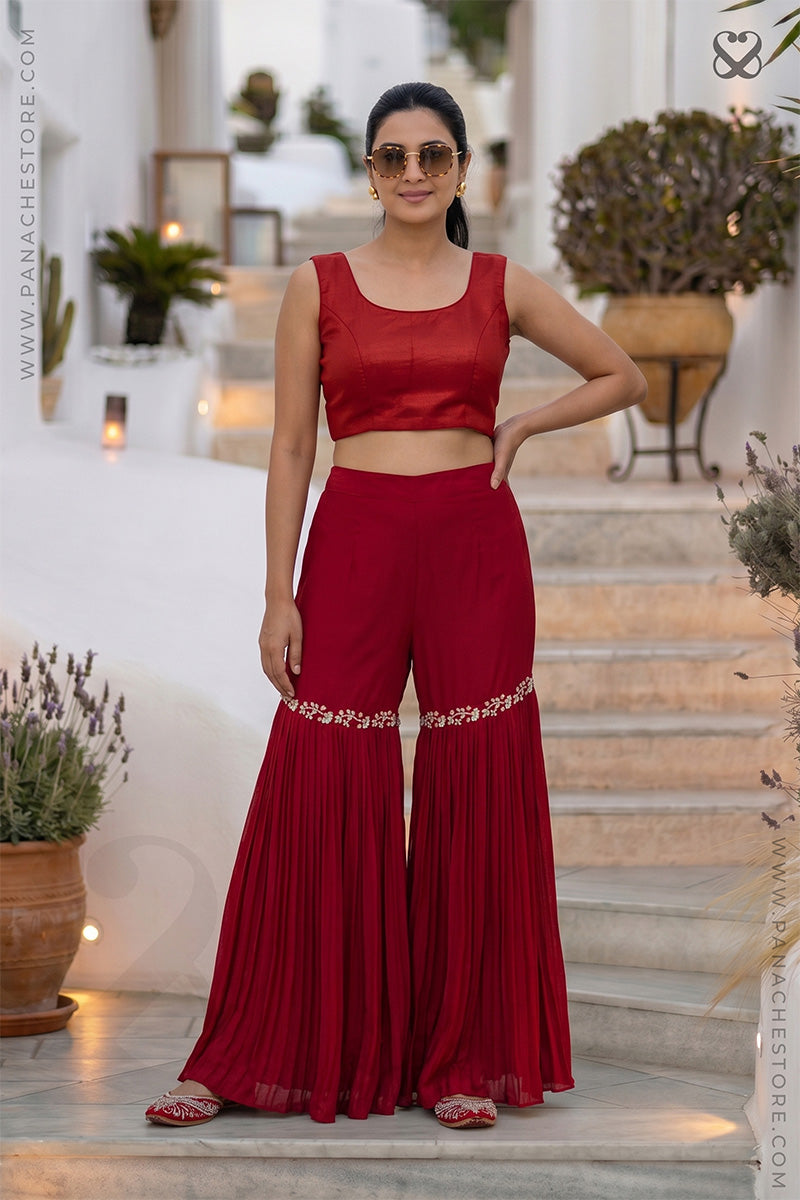 Woman in a red blouse bustier with sharara pant outfit standing on a steps outdoor setting