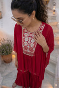 Woman wearing a red dress with intricate floral embroidery in an outdoor setting