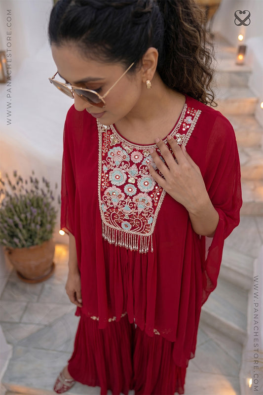 Woman wearing a red dress with intricate floral embroidery in an outdoor setting