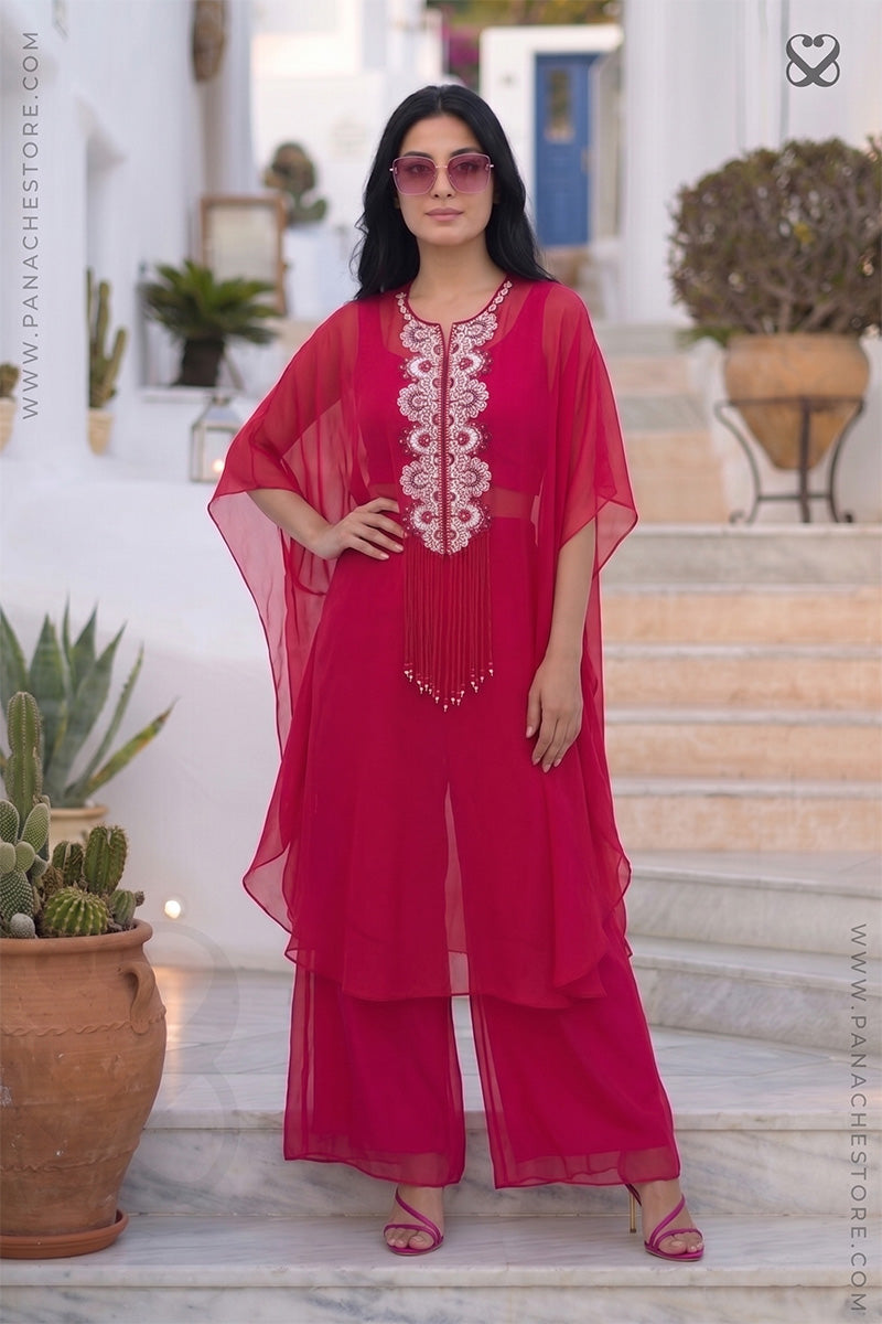 Woman in a red-pink kaftan outfit standing on steps