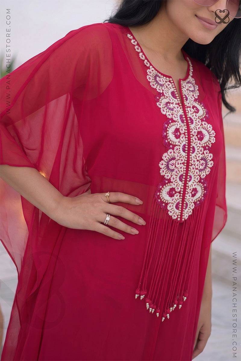 Woman in a red-pink kaftan outfit with embroidered 