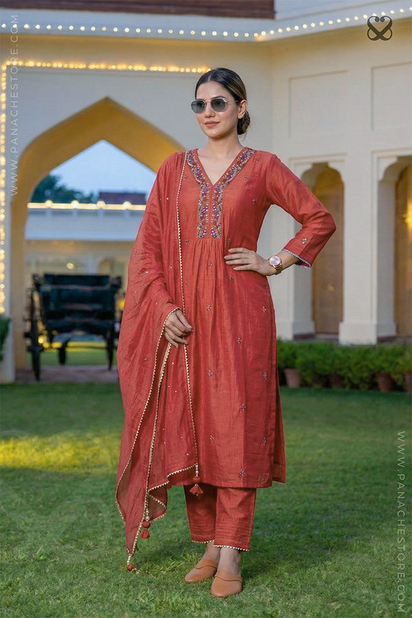Woman in a red salwar suit set with dupatta standing in garden