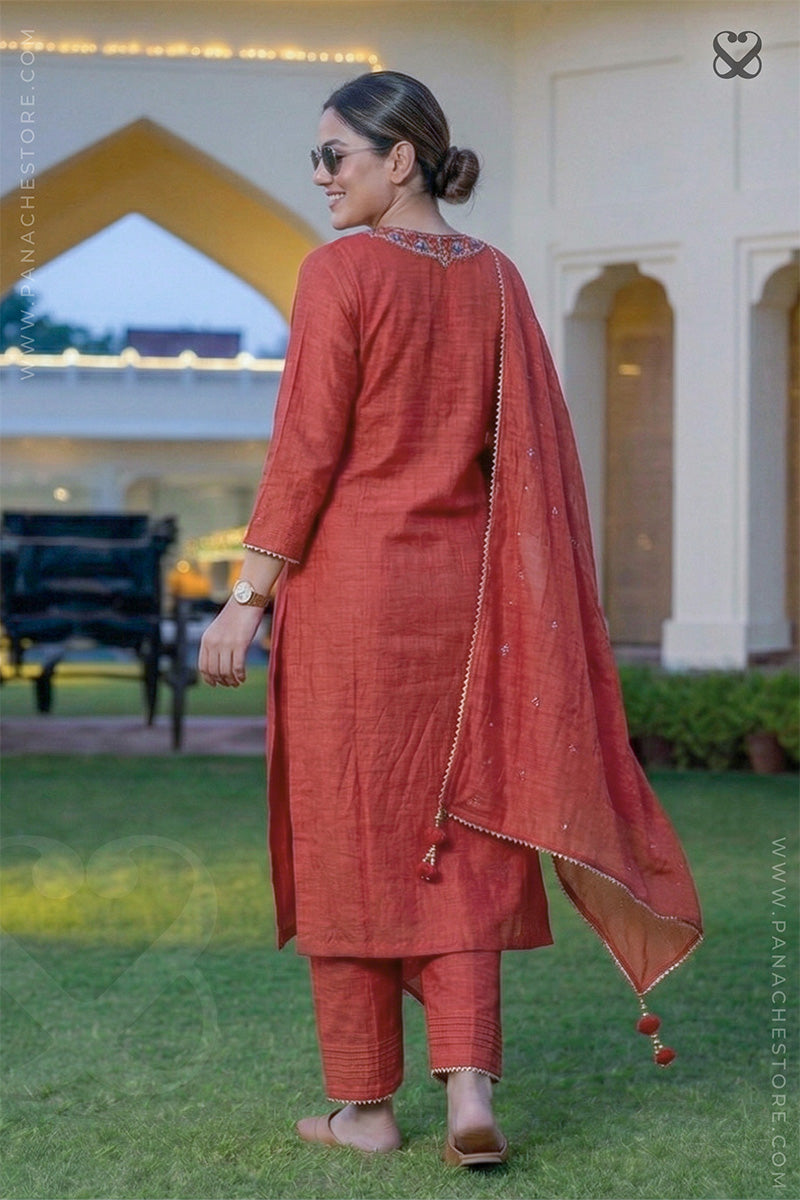 Woman in a red salwar suit set with dupatta standing back pose in garden