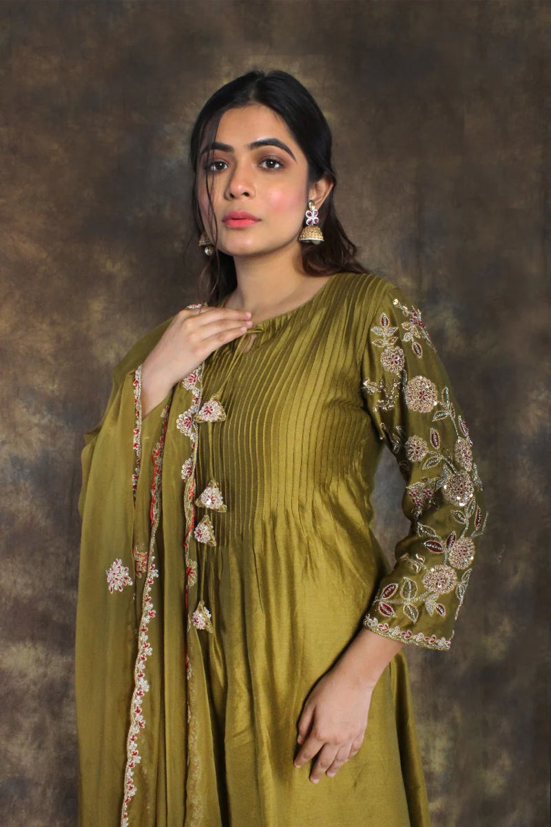Woman wearing a henna green salwar suit and dupatta with a textured brown background