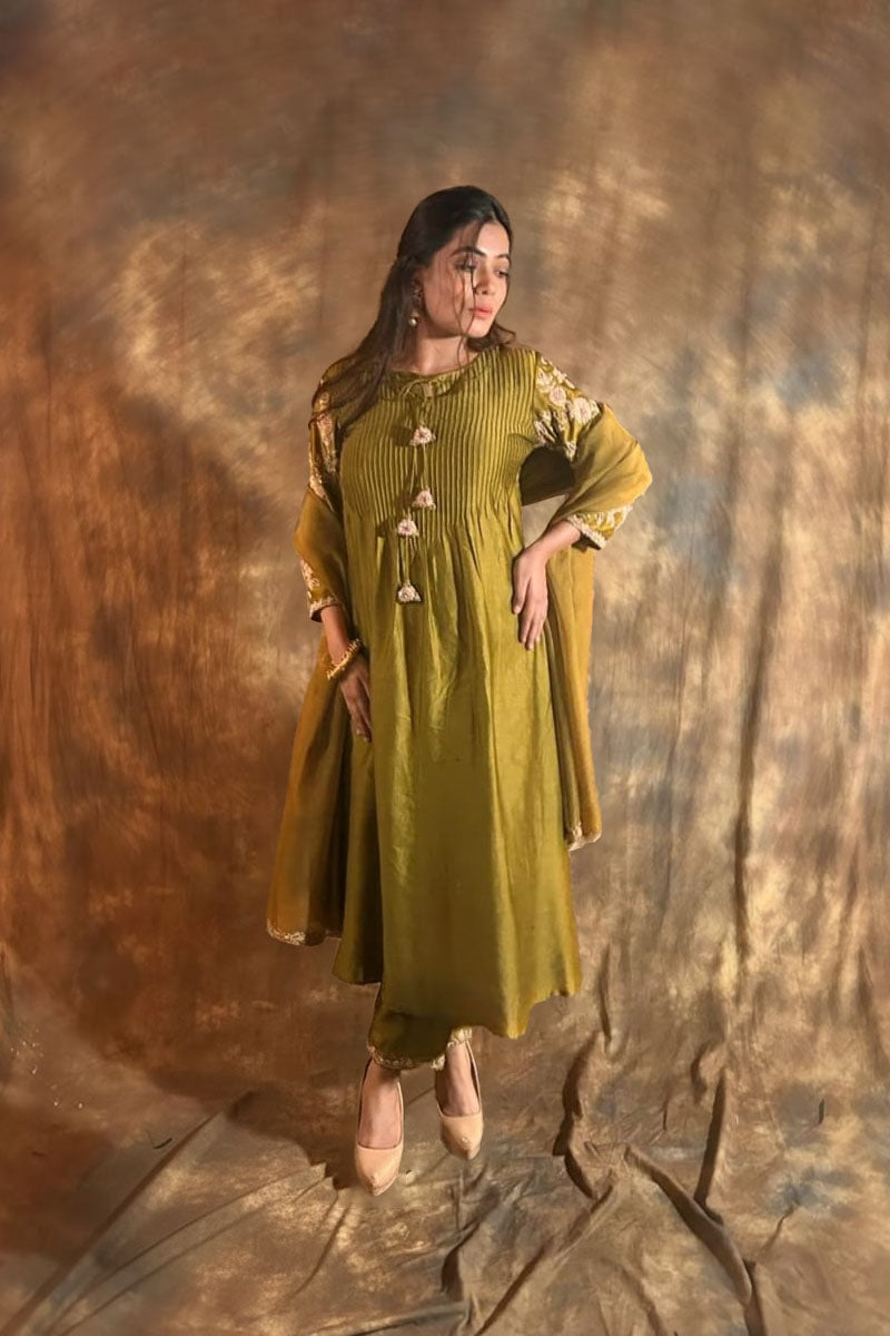 Woman wearing a henna green salwar suit and dupatta with a textured brown background