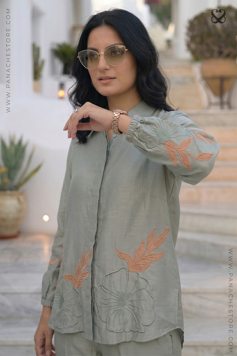 Woman in a light green co ord outfit set with floral embroidery & aplique work standing on steps