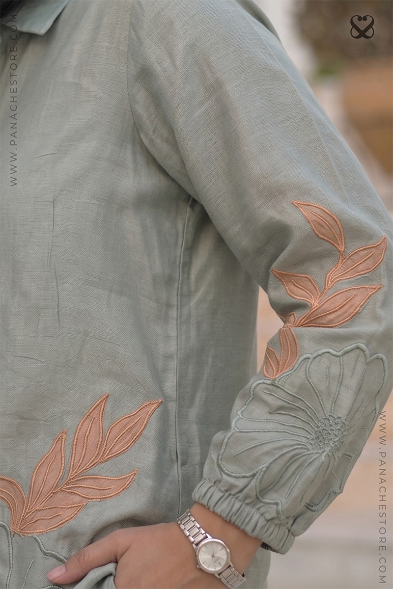 Green shirt with floral embroidery and aplique on sleeve and cuff, worn by a woman