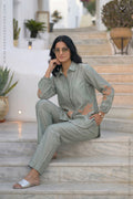 Woman in a light green co ord outfit set with floral aplique work sitting on steps