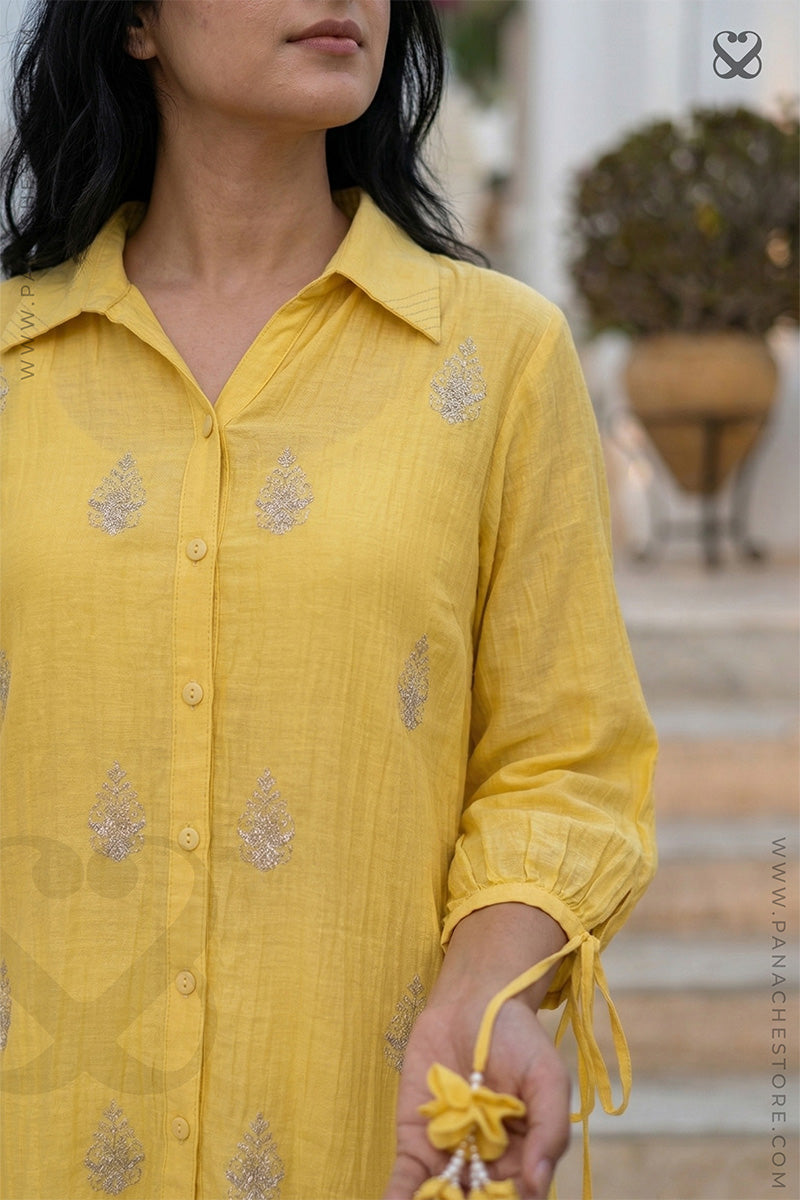 Yellow embroidered shirt worn by a person with a blurred outdoor background
