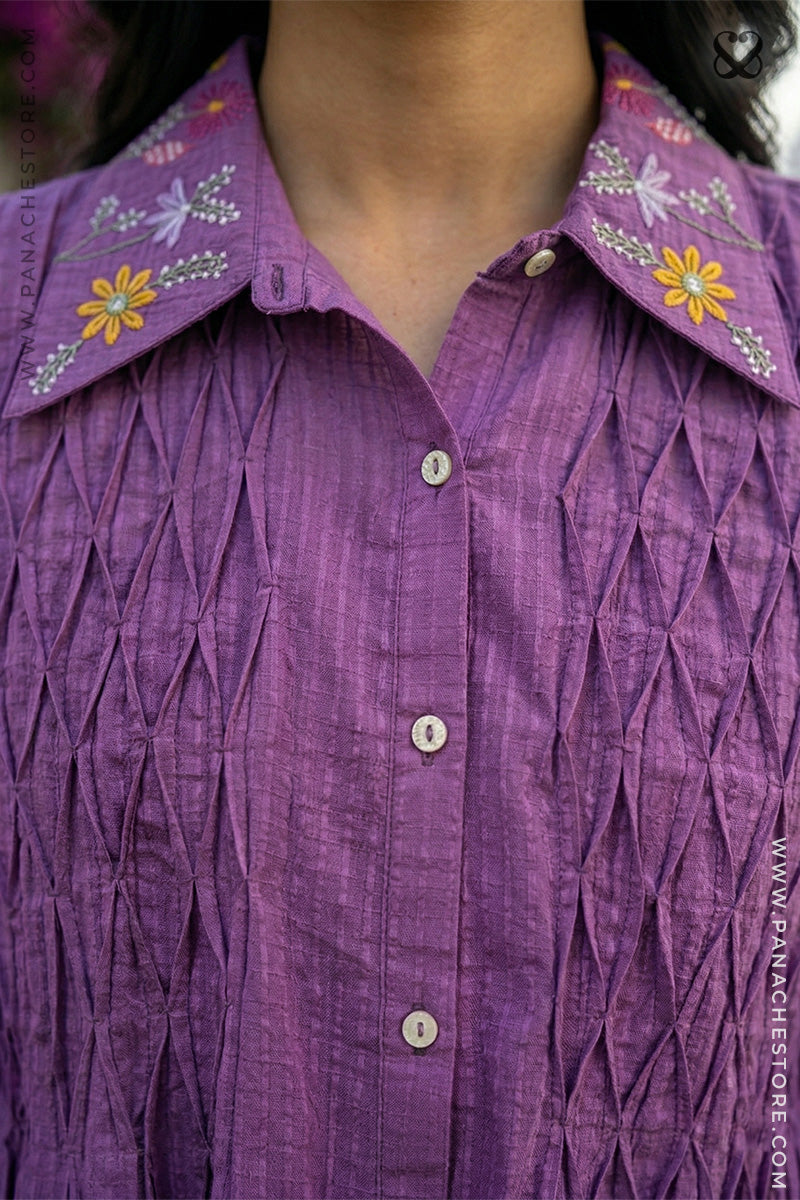 Close-up of a purple shirt with floral embroidery on the collar.